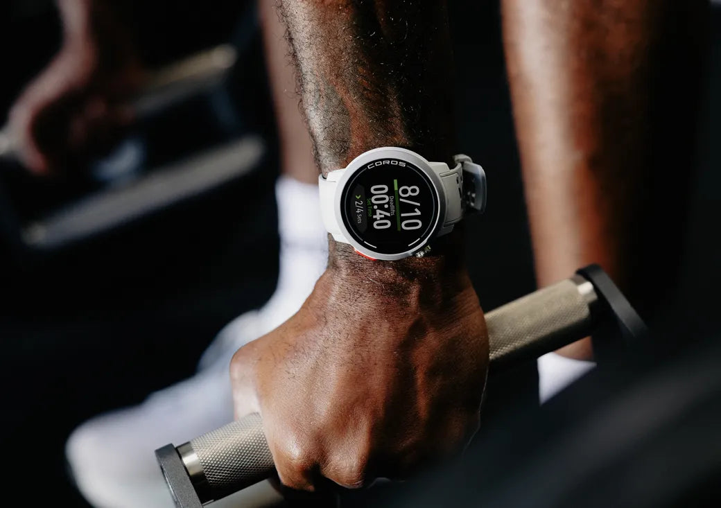 Person holding dumbbells with a smartwatch on wrist displaying time and steps.