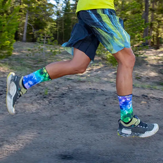 Courtney Dawaulter running outdoors wearing colorful socks and shorts with a forest background