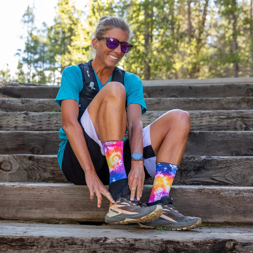 Courtney Dawaulter sitting on wooden steps outdoors wearing colorful socks and sunglasses.