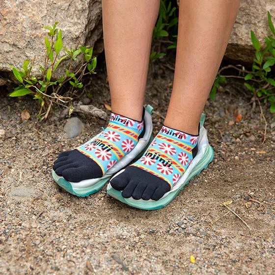 Person wearing colorful toe-shaped socks on a natural ground surface