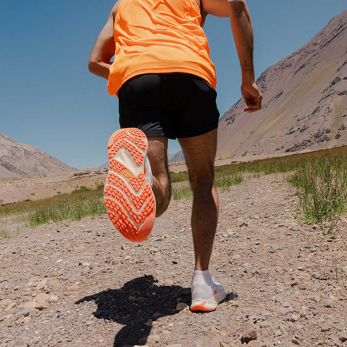 Person running on a dirt path with mountains in the background