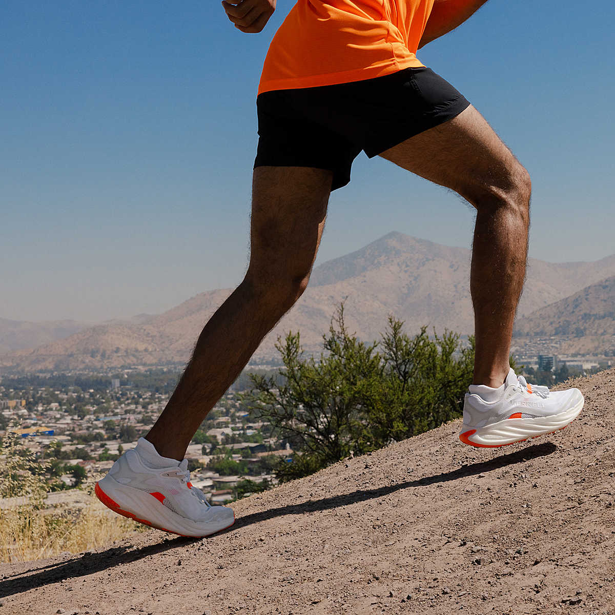 Person running on a trail with mountains and cityscape in the background