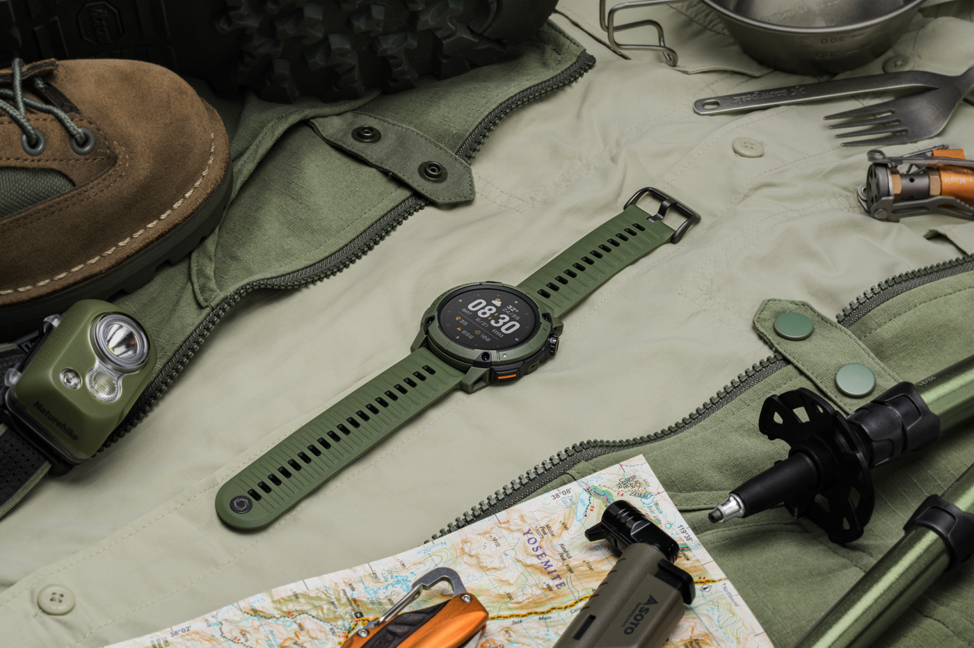Green smartwatch on a green jacket with hiking gear around