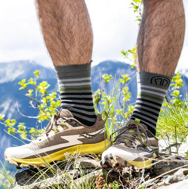 Person wearing running shoes and socks with a mountainous background