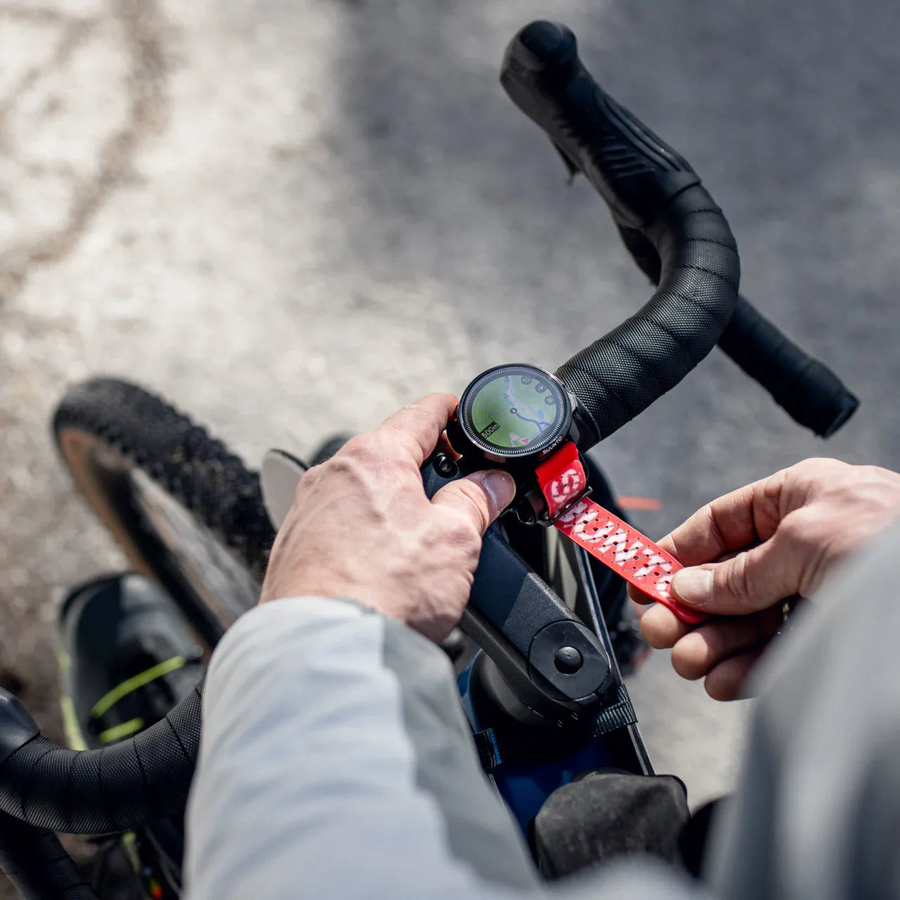 Person adjusting a bike handlebar with a smart watch attached, on a blurred road background