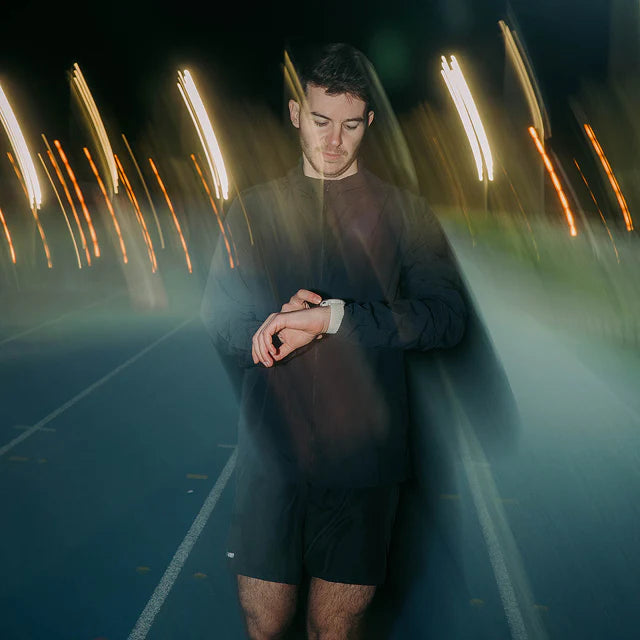 Person standing on a track with light streaks in the background