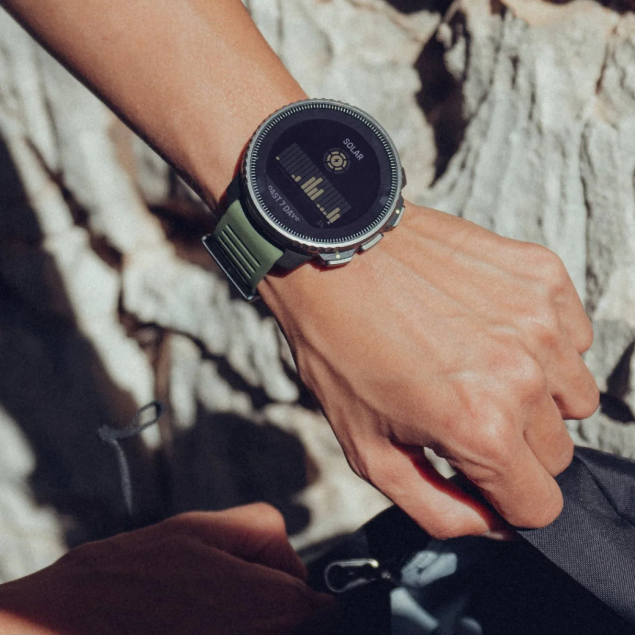 Person wearing a smartwatch with rocks in the background