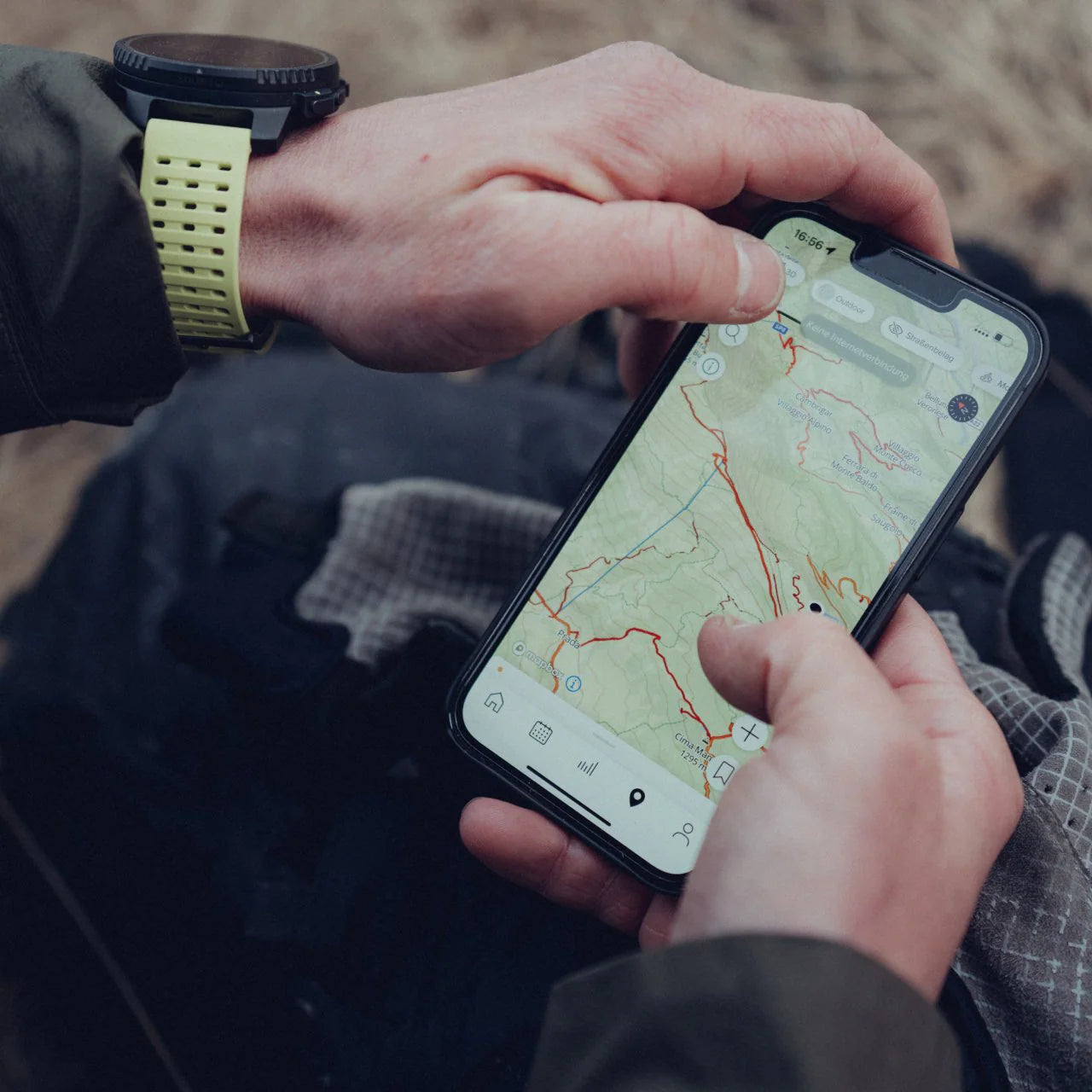 Person holding a smartphone with a map app open, wearing a watch with a yellow strap.