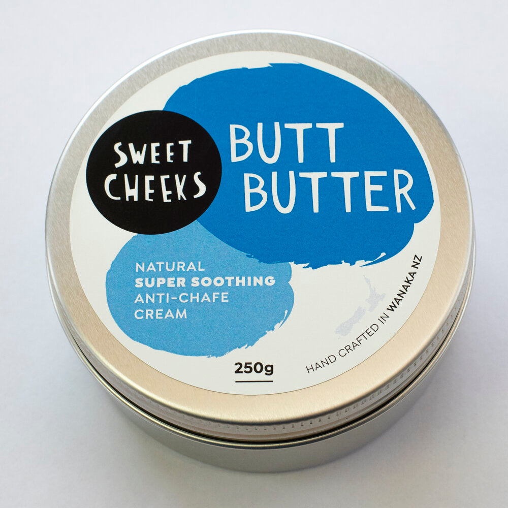 A container of Sweet Cheeks Butt Butter is displayed amidst raw beeswax chunks, highlighting the product's natural and beeswax-based ingredients.
