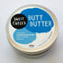 A container of Sweet Cheeks Butt Butter is displayed amidst raw beeswax chunks, highlighting the product's natural and beeswax-based ingredients.